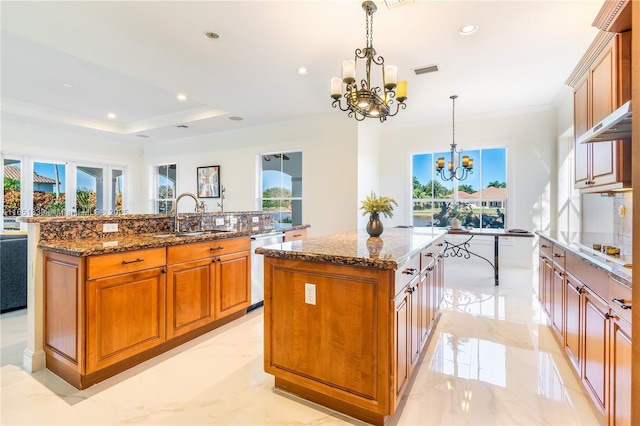 kitchen with a center island, marble finish floor, decorative light fixtures, an inviting chandelier, and a sink