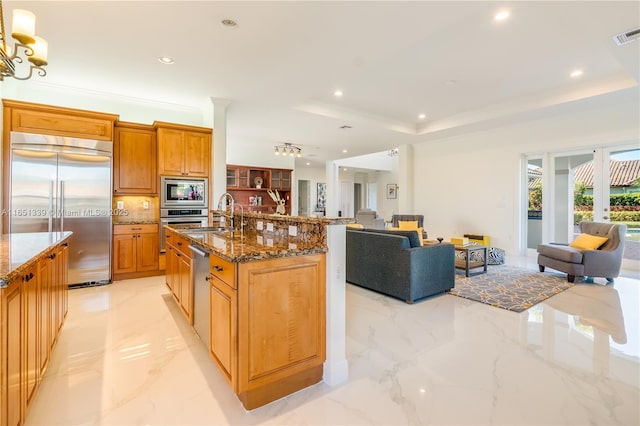 kitchen with a tray ceiling, marble finish floor, a large island, open floor plan, and built in appliances