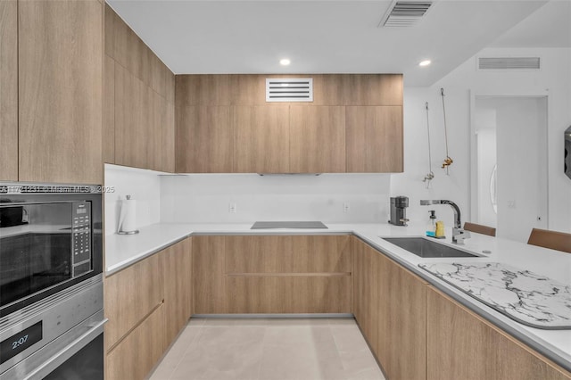 kitchen with oven, sink, built in microwave, light brown cabinetry, and light tile patterned flooring