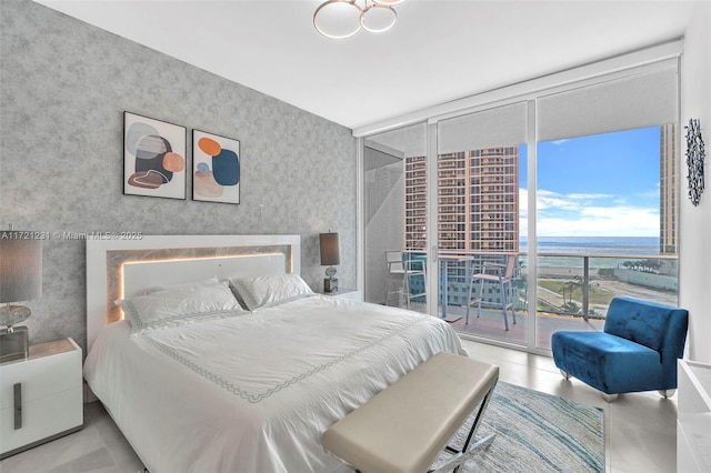 bedroom with access to exterior, a water view, and floor to ceiling windows