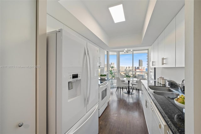 kitchen with floor to ceiling windows, white appliances, sink, and white cabinetry