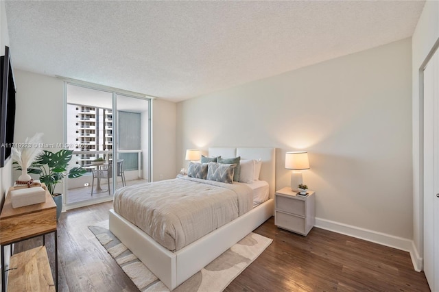 bedroom featuring expansive windows, dark hardwood / wood-style flooring, a textured ceiling, and access to outside