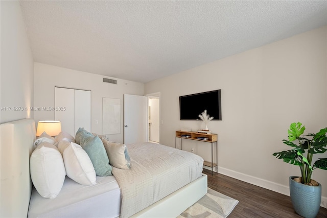 bedroom featuring dark hardwood / wood-style flooring, a textured ceiling, and a closet