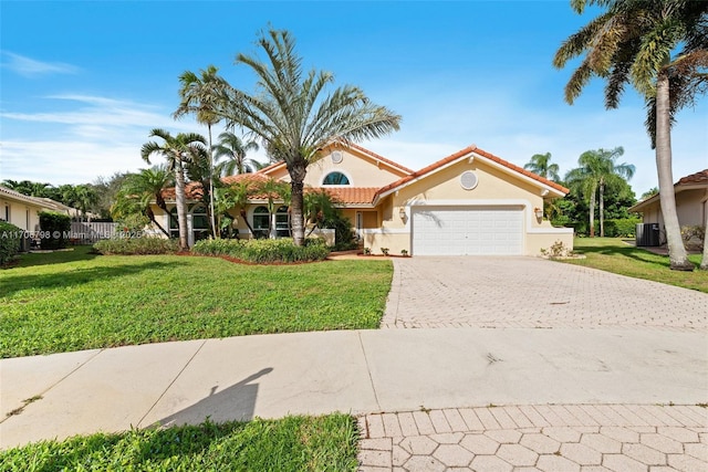 mediterranean / spanish home with cooling unit, a garage, and a front lawn