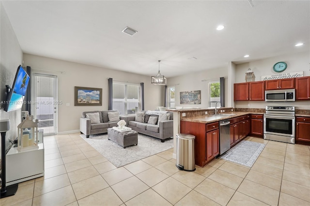 kitchen featuring appliances with stainless steel finishes, sink, light tile patterned floors, decorative light fixtures, and a chandelier