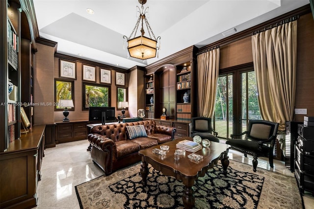 living area with ornamental molding and a raised ceiling