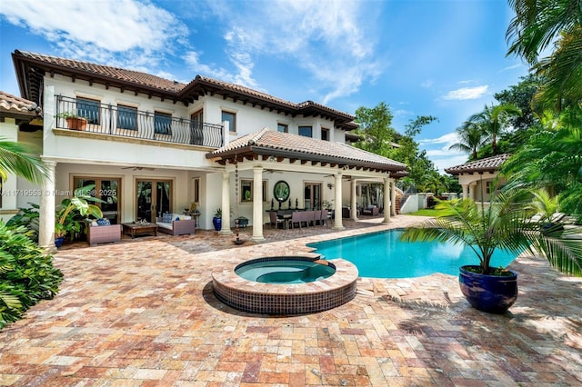 back of house with a pool with hot tub, ceiling fan, a patio area, an outdoor hangout area, and a balcony