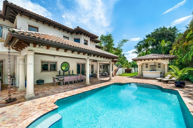 rear view of house with ceiling fan, an outdoor bar, and a patio