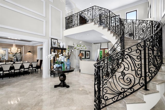 stairway with an inviting chandelier, crown molding, and a towering ceiling