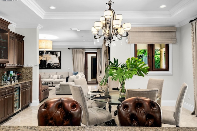 dining room with an inviting chandelier, crown molding, beverage cooler, and a tray ceiling