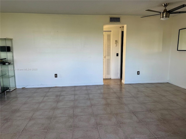 unfurnished room with baseboards, visible vents, and a ceiling fan