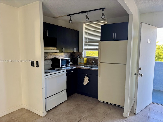 kitchen with white appliances, decorative backsplash, under cabinet range hood, a sink, and light tile patterned flooring