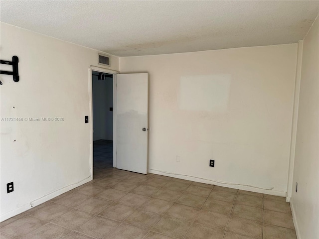 unfurnished room with baseboards, visible vents, and a textured ceiling