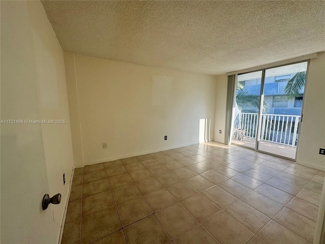 spare room featuring tile patterned flooring, baseboards, a wall of windows, and a textured ceiling