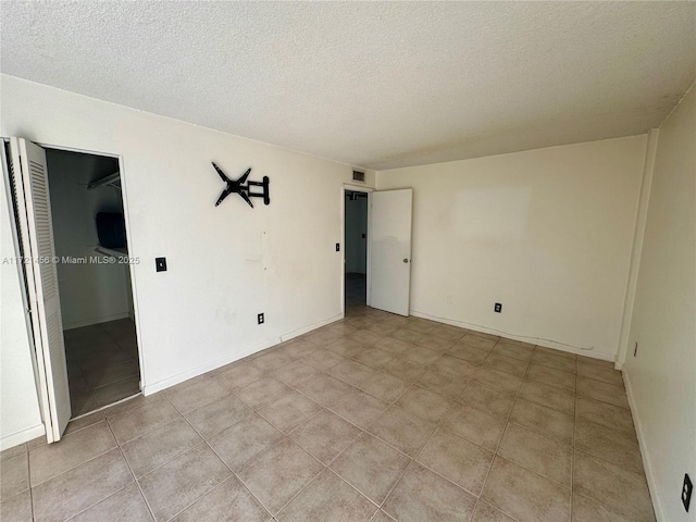 unfurnished room with visible vents, a textured ceiling, and light tile patterned floors