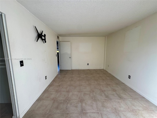 spare room featuring a textured ceiling and baseboards