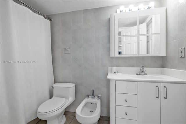 bathroom featuring vanity, a bidet, tile patterned flooring, toilet, and tile walls