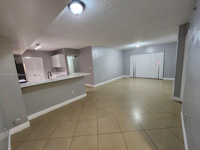 unfurnished living room with light tile patterned floors and a textured ceiling