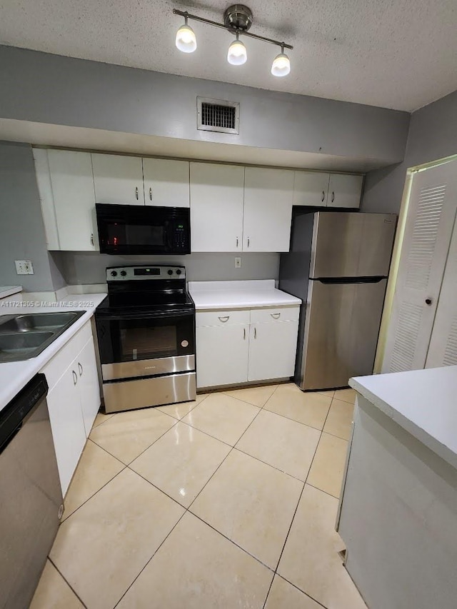 kitchen featuring a textured ceiling, stainless steel appliances, sink, light tile patterned floors, and white cabinets