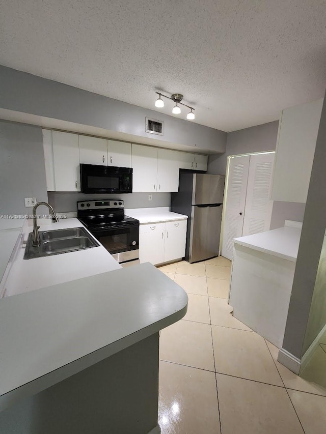 kitchen with sink, light tile patterned floors, appliances with stainless steel finishes, a textured ceiling, and white cabinets