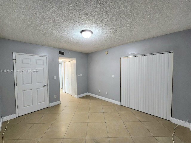 unfurnished bedroom with a textured ceiling and light tile patterned flooring