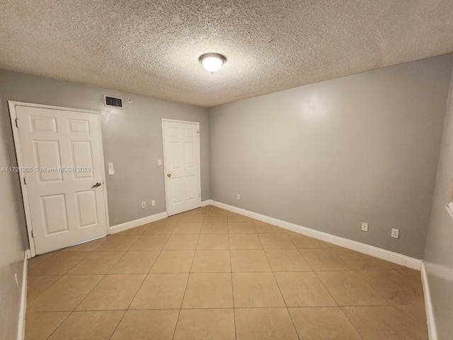 unfurnished room featuring light tile patterned floors and a textured ceiling