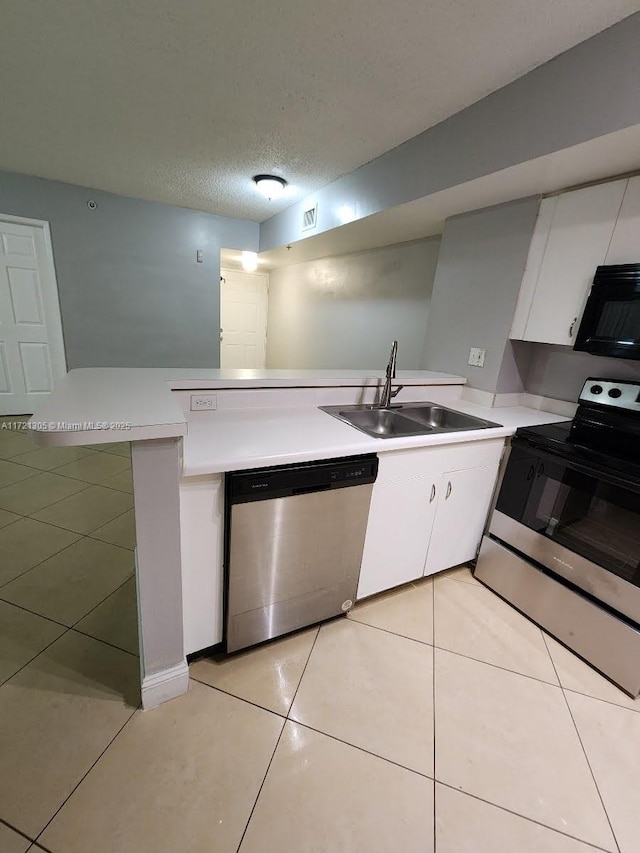 kitchen featuring sink, light tile patterned floors, appliances with stainless steel finishes, white cabinetry, and kitchen peninsula