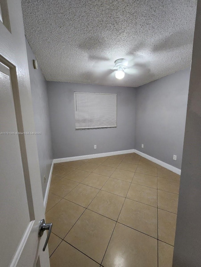 spare room with tile patterned flooring and a textured ceiling