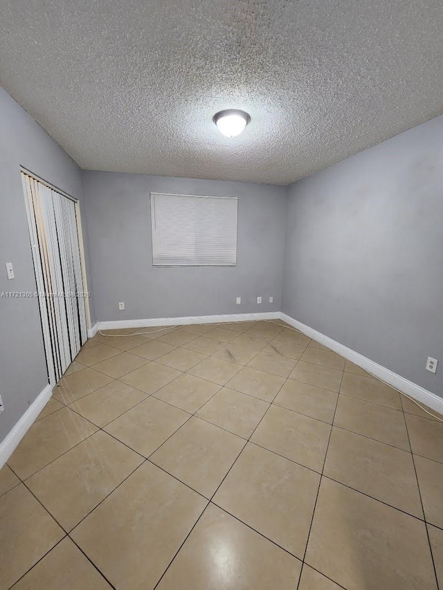 unfurnished bedroom with light tile patterned floors, a closet, and a textured ceiling