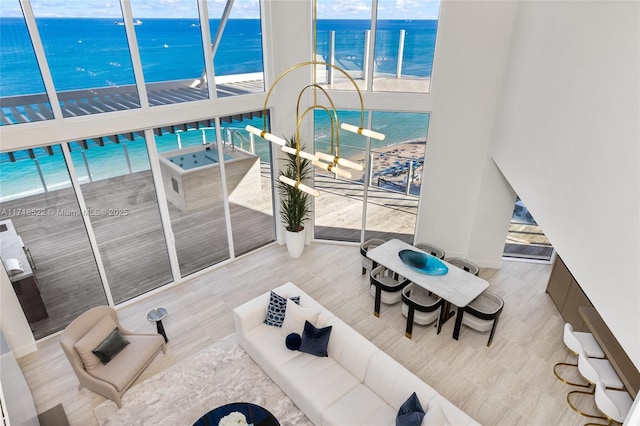 living room featuring a beach view, light wood-type flooring, and a water view