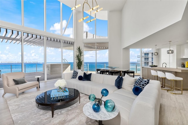 living room with plenty of natural light, a water view, and an inviting chandelier