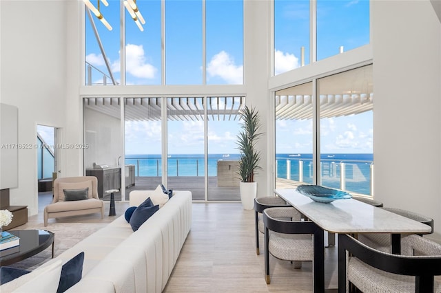 living room featuring light hardwood / wood-style floors, a water view, and a high ceiling