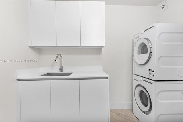 clothes washing area with cabinets, sink, and stacked washer and clothes dryer