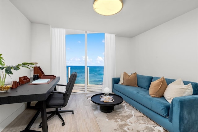 home office featuring a water view, wood-type flooring, and a wall of windows