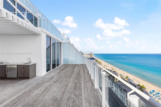 balcony with area for grilling, sink, a water view, and a view of the beach