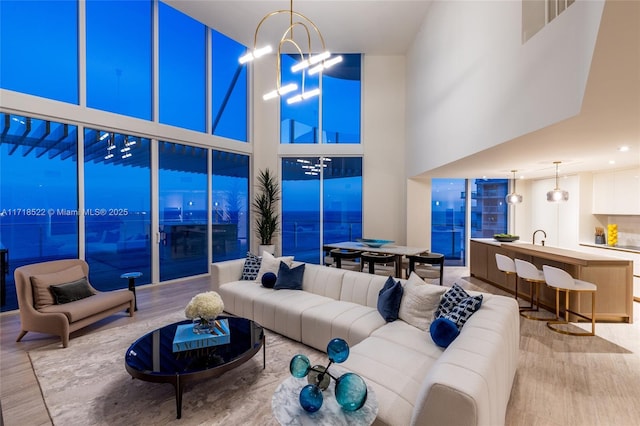 living room featuring hardwood / wood-style flooring, a notable chandelier, and a towering ceiling