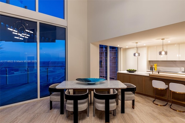 dining room with sink, a towering ceiling, and light hardwood / wood-style floors