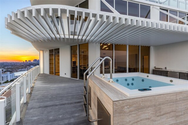 pool at dusk featuring an outdoor hot tub