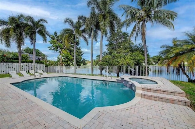 view of swimming pool with a patio area, a water view, and an in ground hot tub