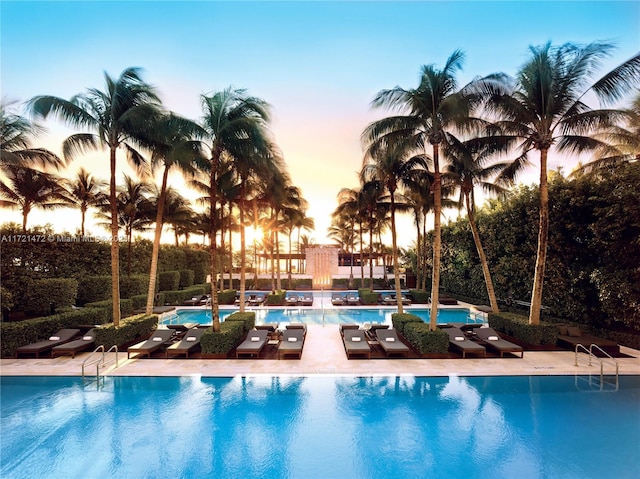 pool at dusk featuring a patio area