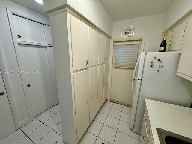 kitchen with white fridge, light tile patterned floors, and sink