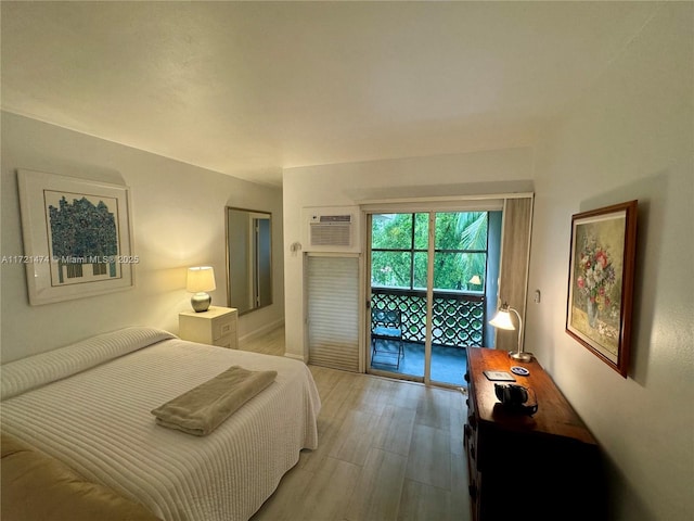 bedroom featuring access to exterior, light wood-type flooring, and a wall unit AC