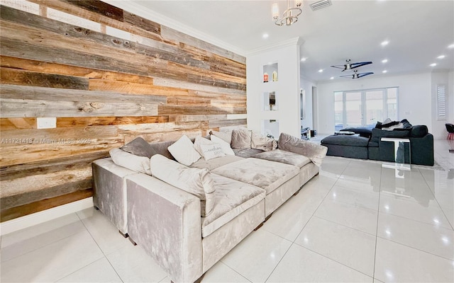 living room with wooden walls, crown molding, light tile patterned floors, and ceiling fan with notable chandelier