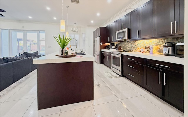 kitchen with backsplash, stainless steel appliances, decorative light fixtures, an island with sink, and light tile patterned flooring