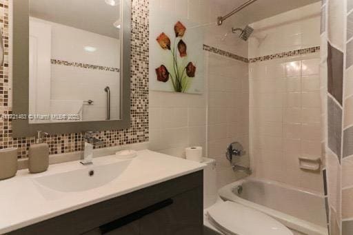 full bathroom featuring toilet, vanity, backsplash, and shower / bath combo