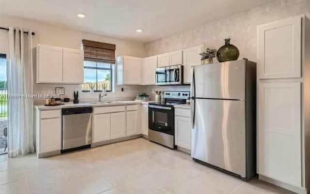 kitchen featuring sink, white cabinets, light tile patterned floors, and appliances with stainless steel finishes