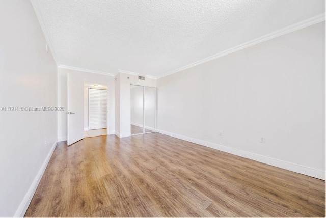 unfurnished room featuring light wood-type flooring, ornamental molding, and a textured ceiling