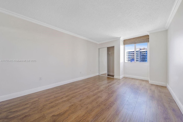 unfurnished room with wood-type flooring, a textured ceiling, and ornamental molding