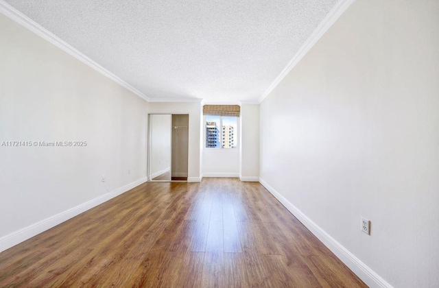 spare room featuring crown molding, dark hardwood / wood-style flooring, and a textured ceiling