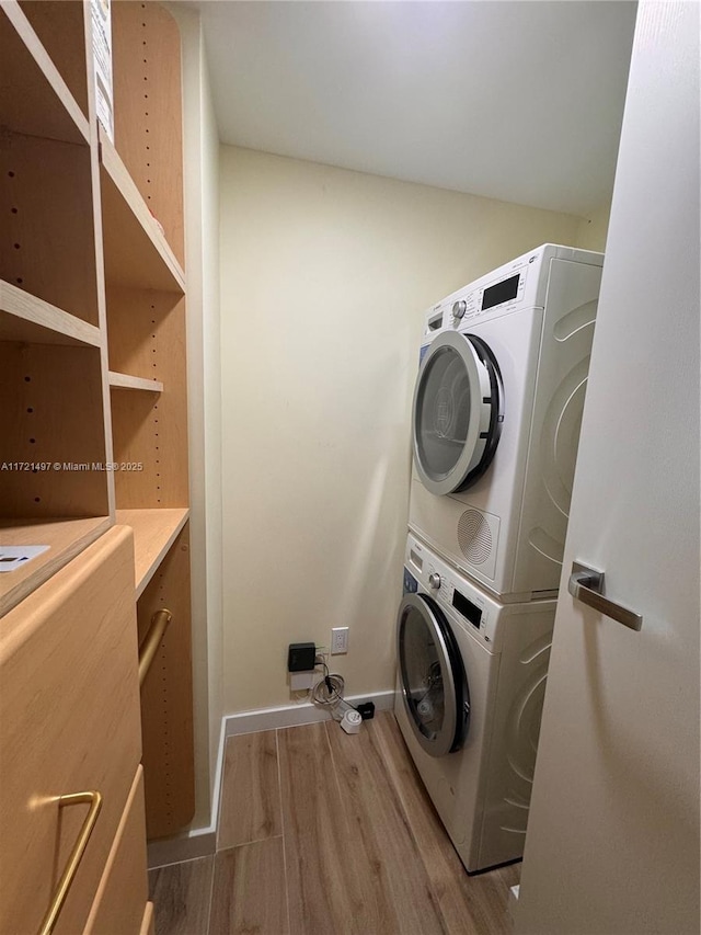 laundry room with light hardwood / wood-style floors and stacked washer / drying machine